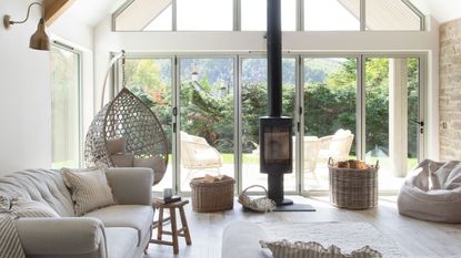 living area with neutral sofas, woodburner and wooden beams