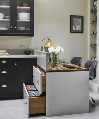 A home office set up in a kitchen with kitchen cupboards used as office storage space