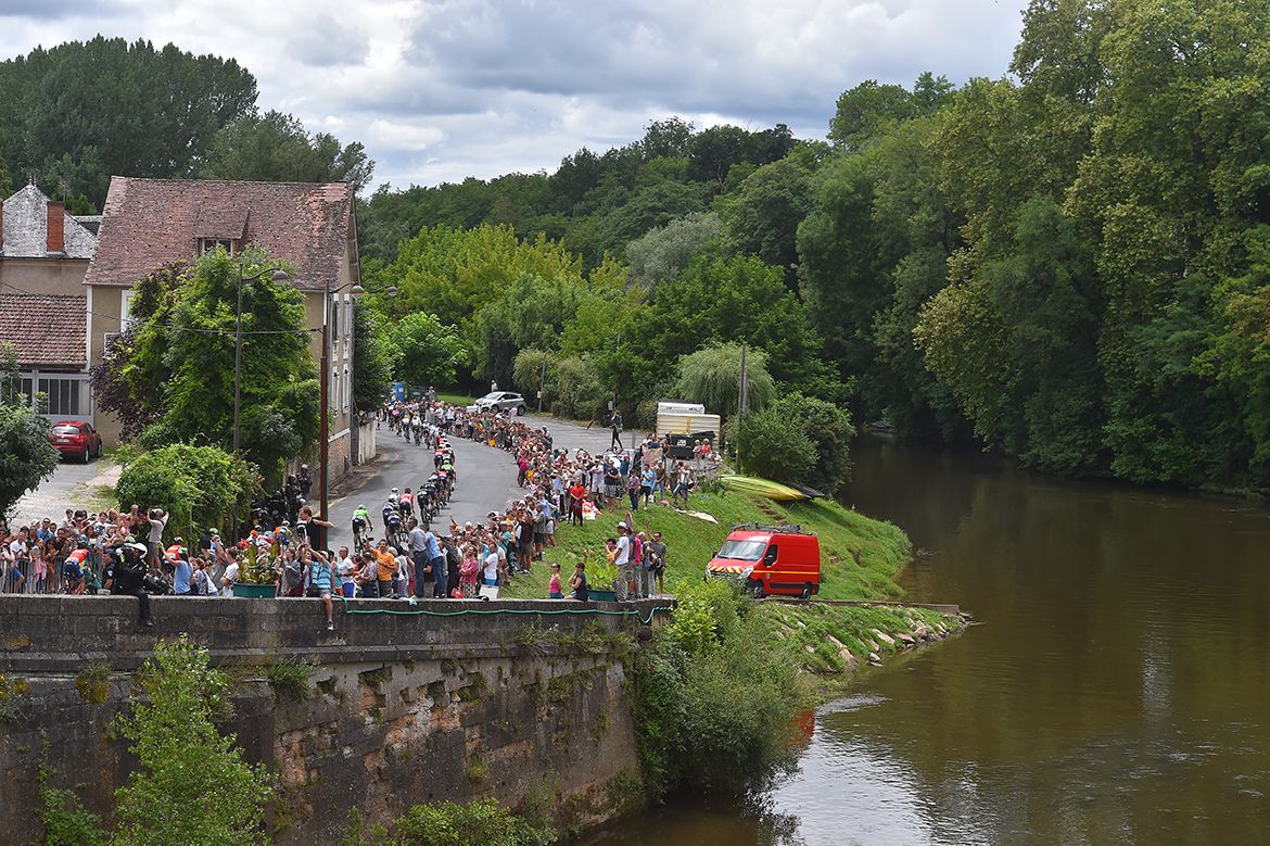 The pack rolls along a riverside on stage 10 of the Tour de France