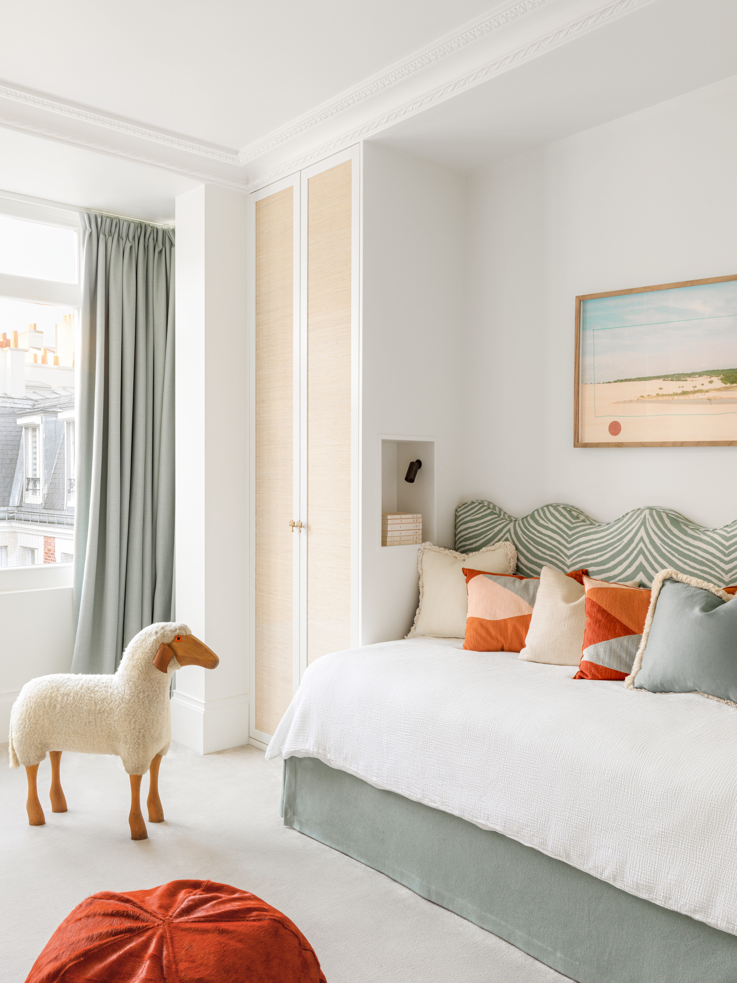Children's room with white walls, cane wardrobe door, mint green curtain and bed upholstery, and sheep toy