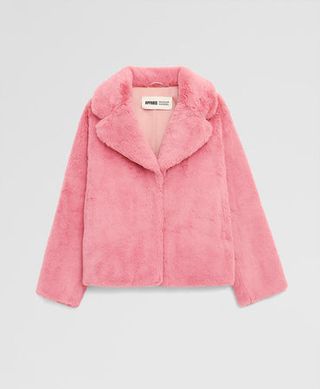 A pink cropped faux fur coat on a plain backdrop