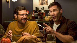 Billy Eichner as Bobby and Luke Macfarlane as Aaron laughing at a dinner table in Bros