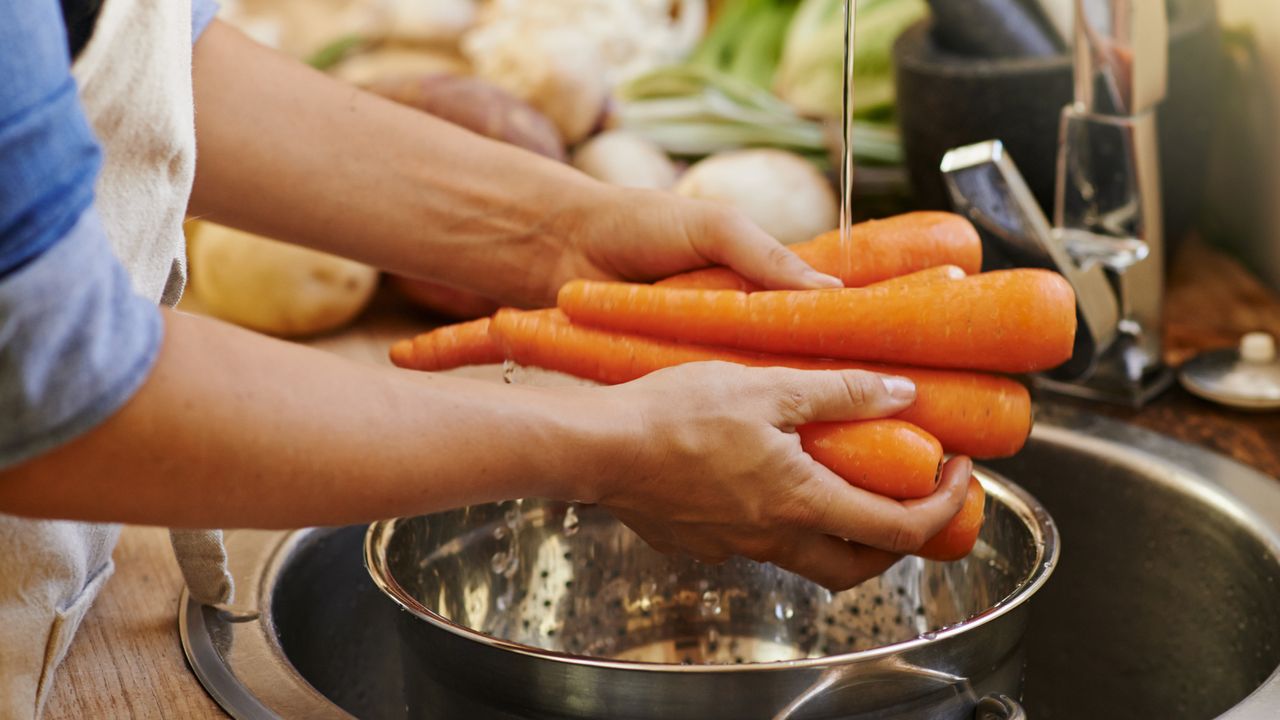 Person washes carrots under a running tap