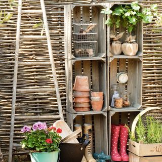 Outdoor wooden storage crates by woven fence