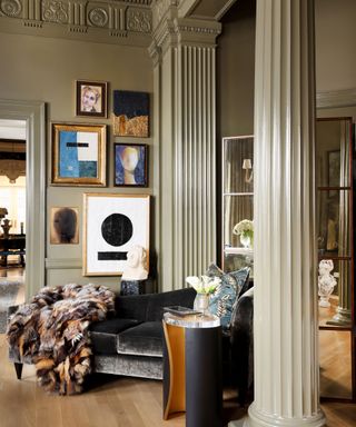 grand living space with gray-green walls, pillar, eclectic gallery wall and velvet chaise lounge