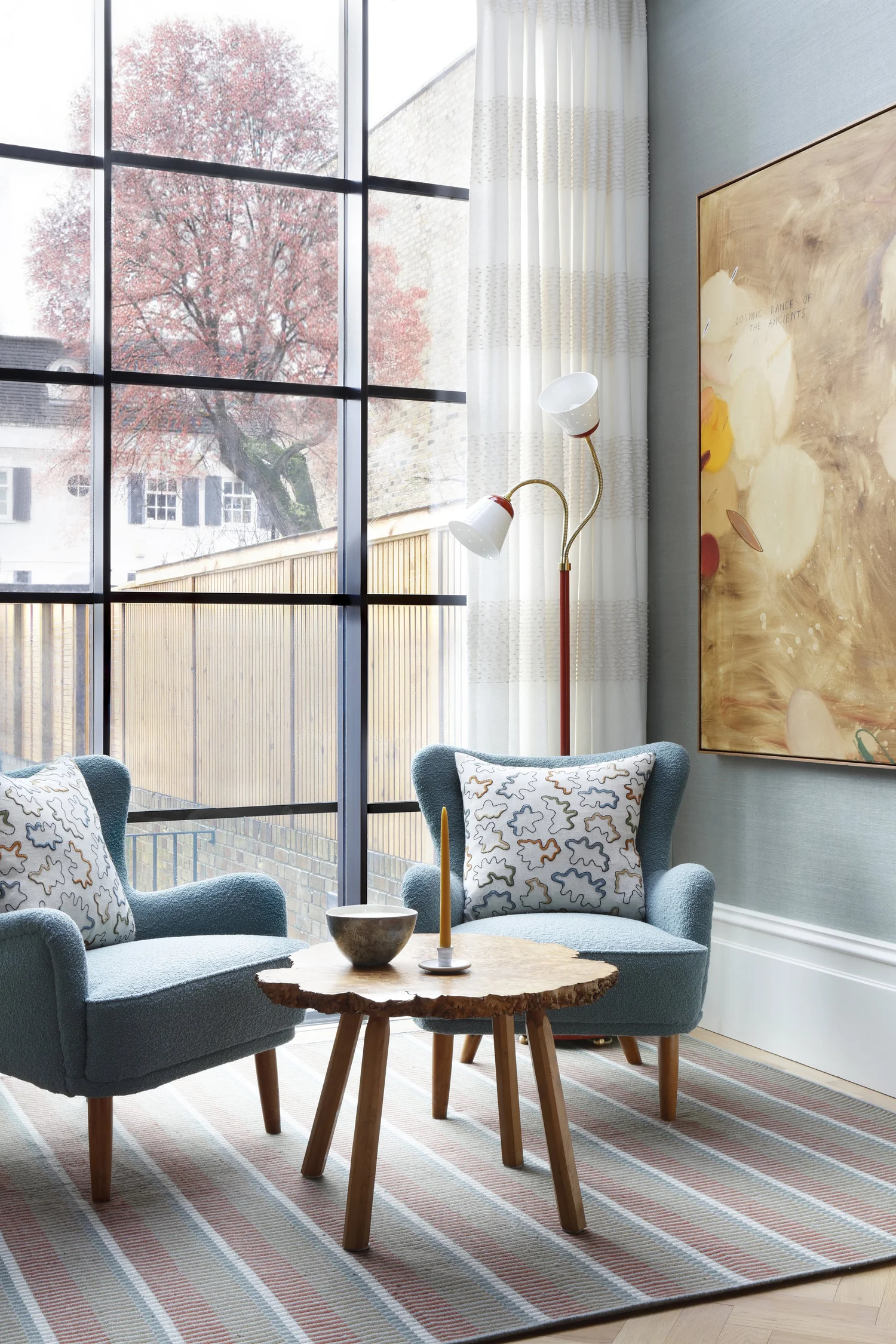 Bright living room with blue armchairs, sheer curtains and metal-framed windows