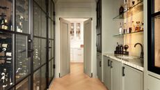 A kitchen with a bar and wine cellar included behind crittall style doors