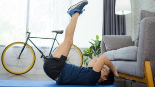 Man performs leg raise abs exercise at home
