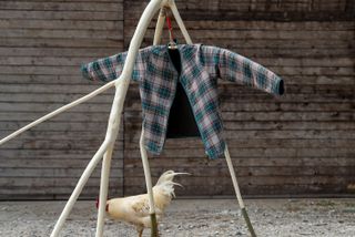 Check jacket by Folk x Architectural Association hanging outdoors on wood