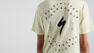The back of a pastel yellow t-shirt with the Specialized S logo and black text