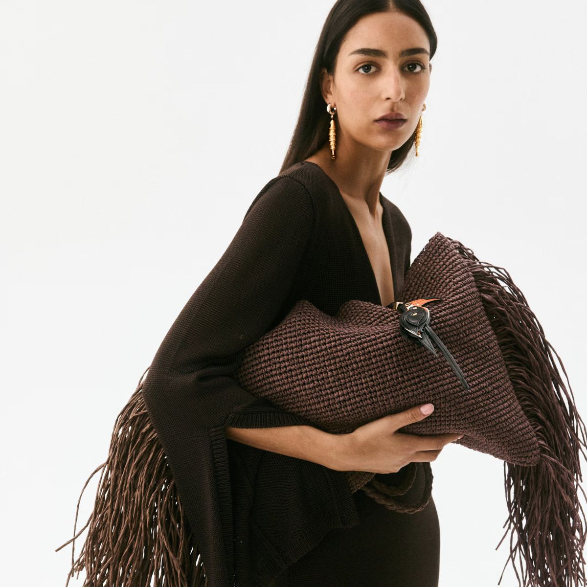 Woman wears brown dress and brown fringed bag
