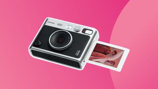A product shot of the Fujifilm Instax Mini Evo camera on a colourful pink background