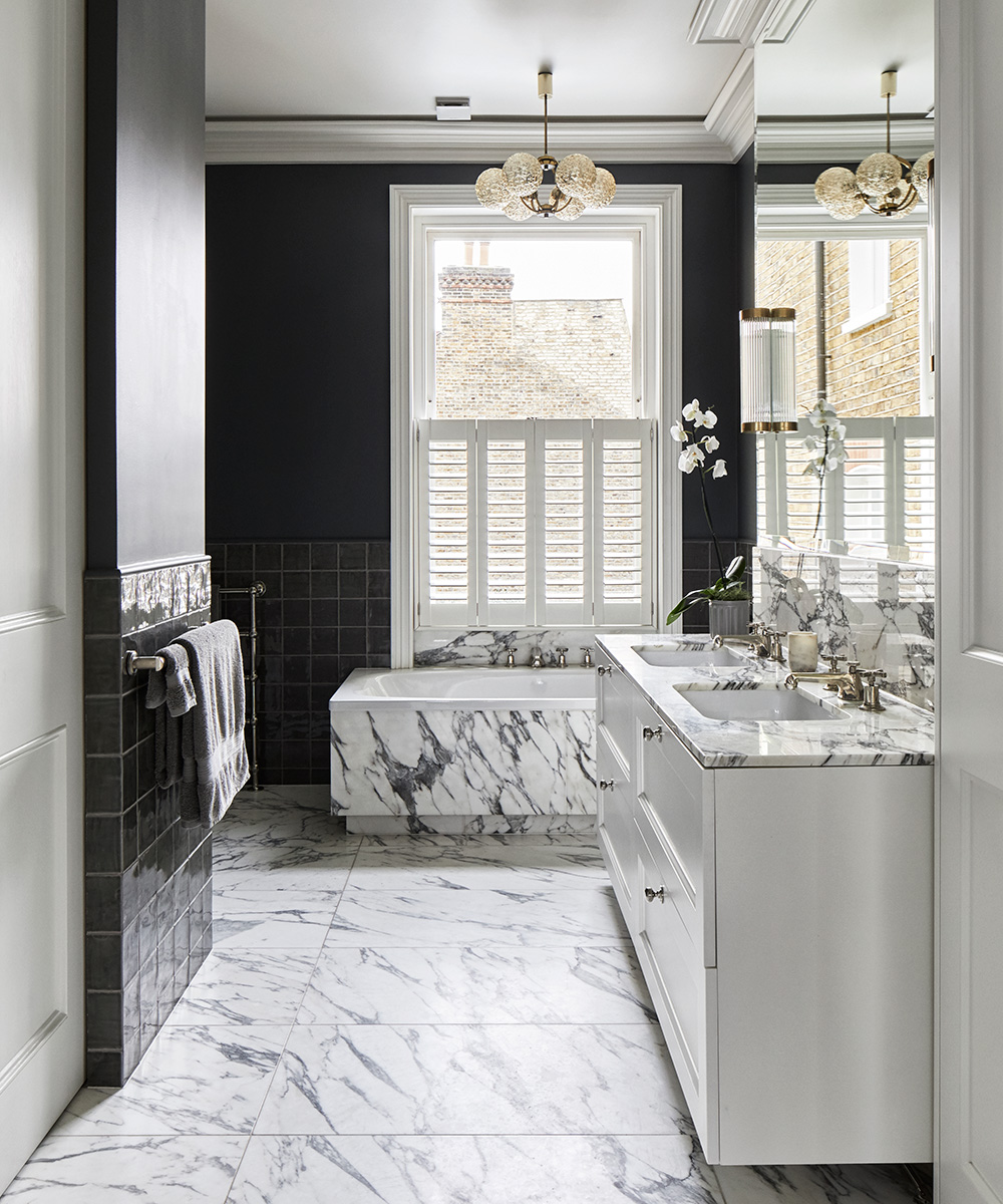 A marble bathroom with black walls and a double vanity unit