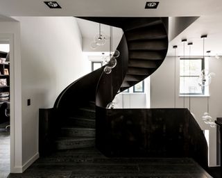 Curved black staircase with pendant lighting