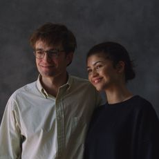 robert pattinson and zendaya as charlie and emma trying to smile and pose for wedding photos in a photo studio in a still from the movie the drama