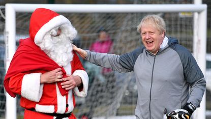 CHEADLE HULME, UNITED KINGDOM - DECEMBER 07: British Prime Minister Boris Johnson greets a man dressed as Father Christmas during the warm up before a girls' soccer match between Hazel Grove 