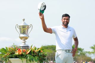 Finau holds his hat and waves to the crowd next to the trophy