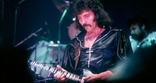 A moustachioed Tony Iommi peels off a solo live with Black Sabbath,1970