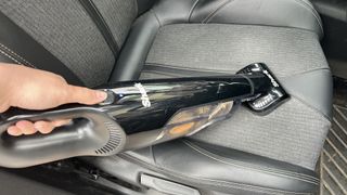 The Shark UltraCyclone Pet Pro Plus handheld vacuum in use on a car seat