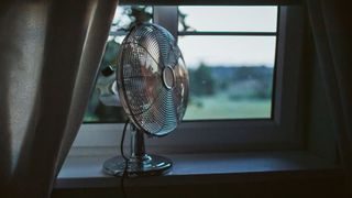 picture of electric fan on at night sat on a windowsill