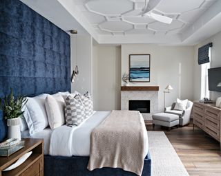 Bedroom with oversized upholstered blue headboard and neutral rug under bed