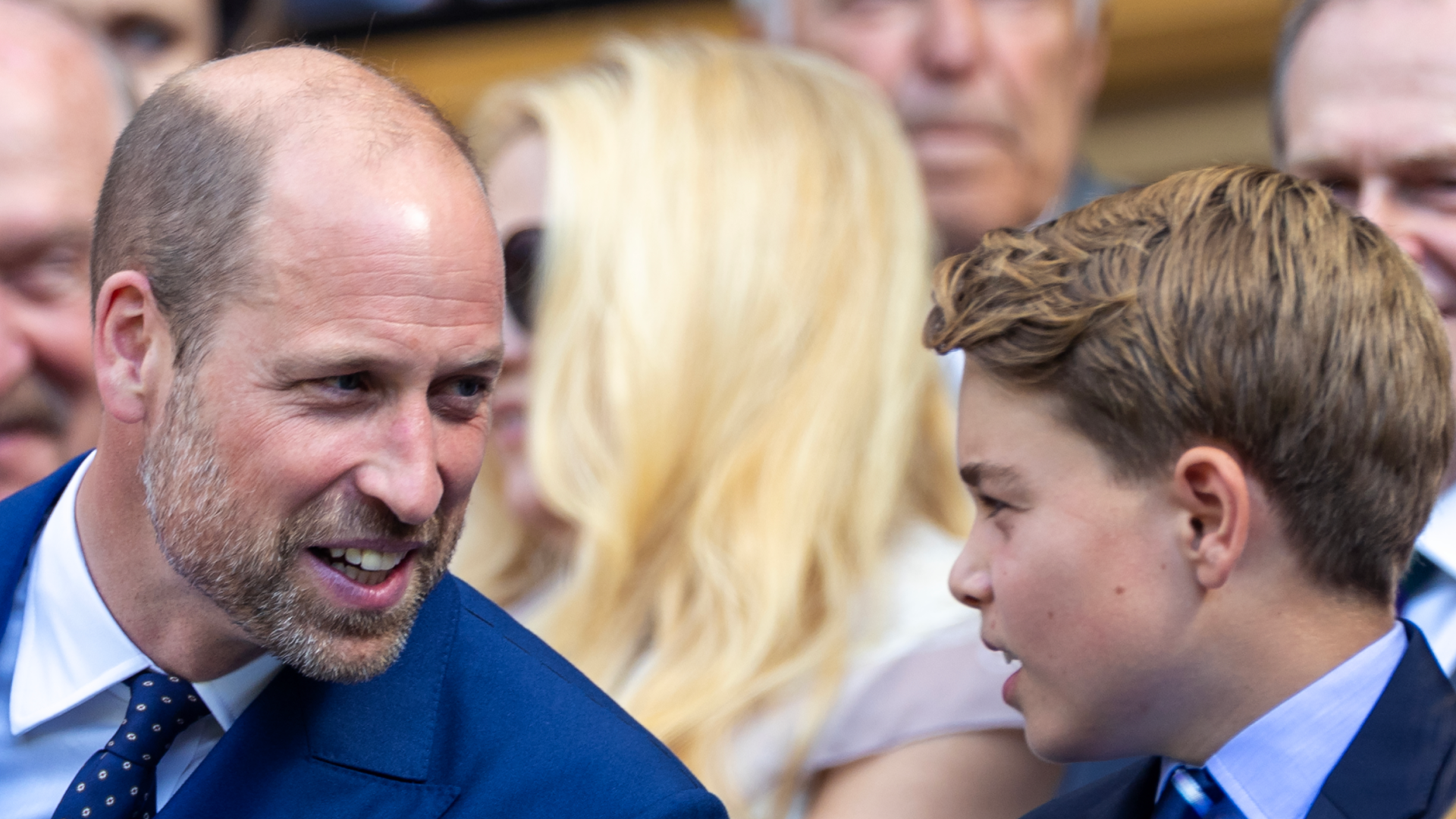 Prince George sitting next to Prince William at Wimbledon, both wearing blue suits