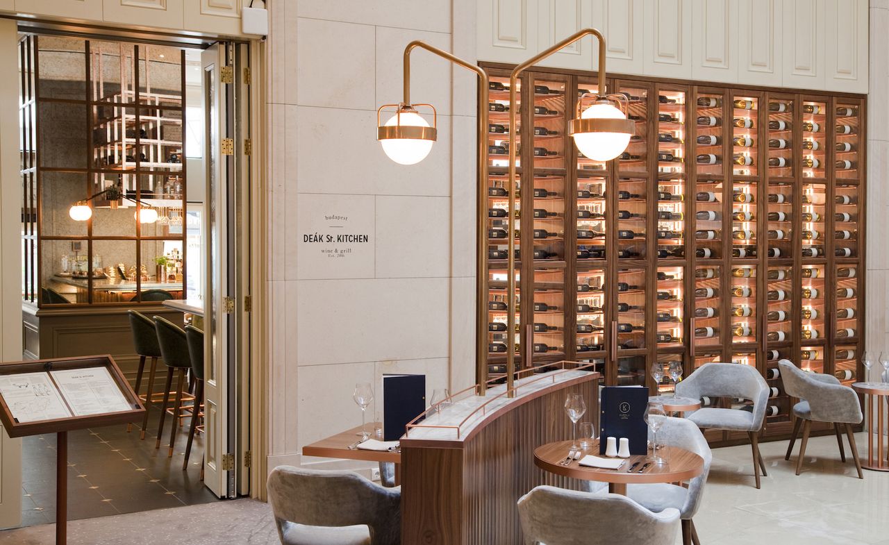 Dining area with ivory suede chairs and copper pipe lighting. Wine store to the right