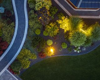 Elegant Residential Landscaped Back Yard Garden Illuminated by Outdoor Lights Aerial View