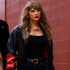 Taylor Swift enters Arrowhead Stadium for the Chiefs Game wearing a leather jacket with a T-shirt, belt by The Row, and Louboutin cowboy boots