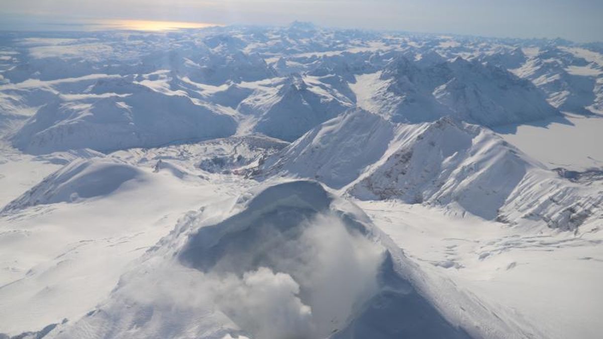 an aerial view of a snowy volcano and mountain range