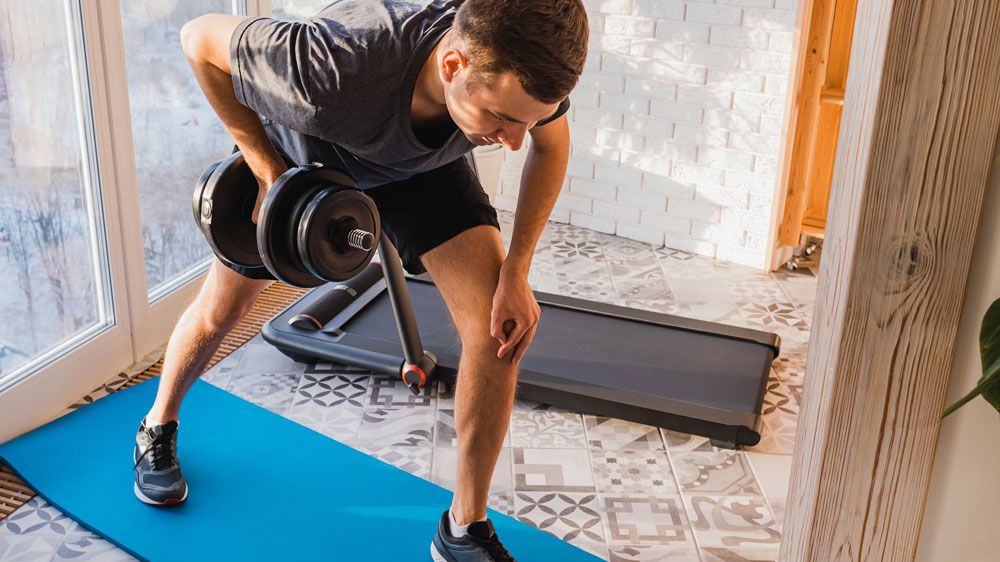 Man performs single-arm dumbbell row at home