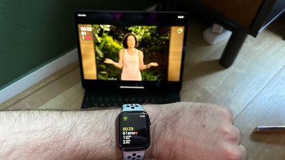 Man showing fitness stats on an Apple Watch while doing an Apple Fitness+ class