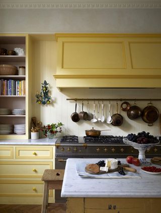 A range oven in a yellow rustic kitchen where food is being prepared