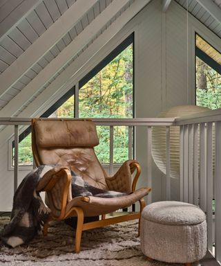 armchair in cabin with white painted wood walls and windows in apex