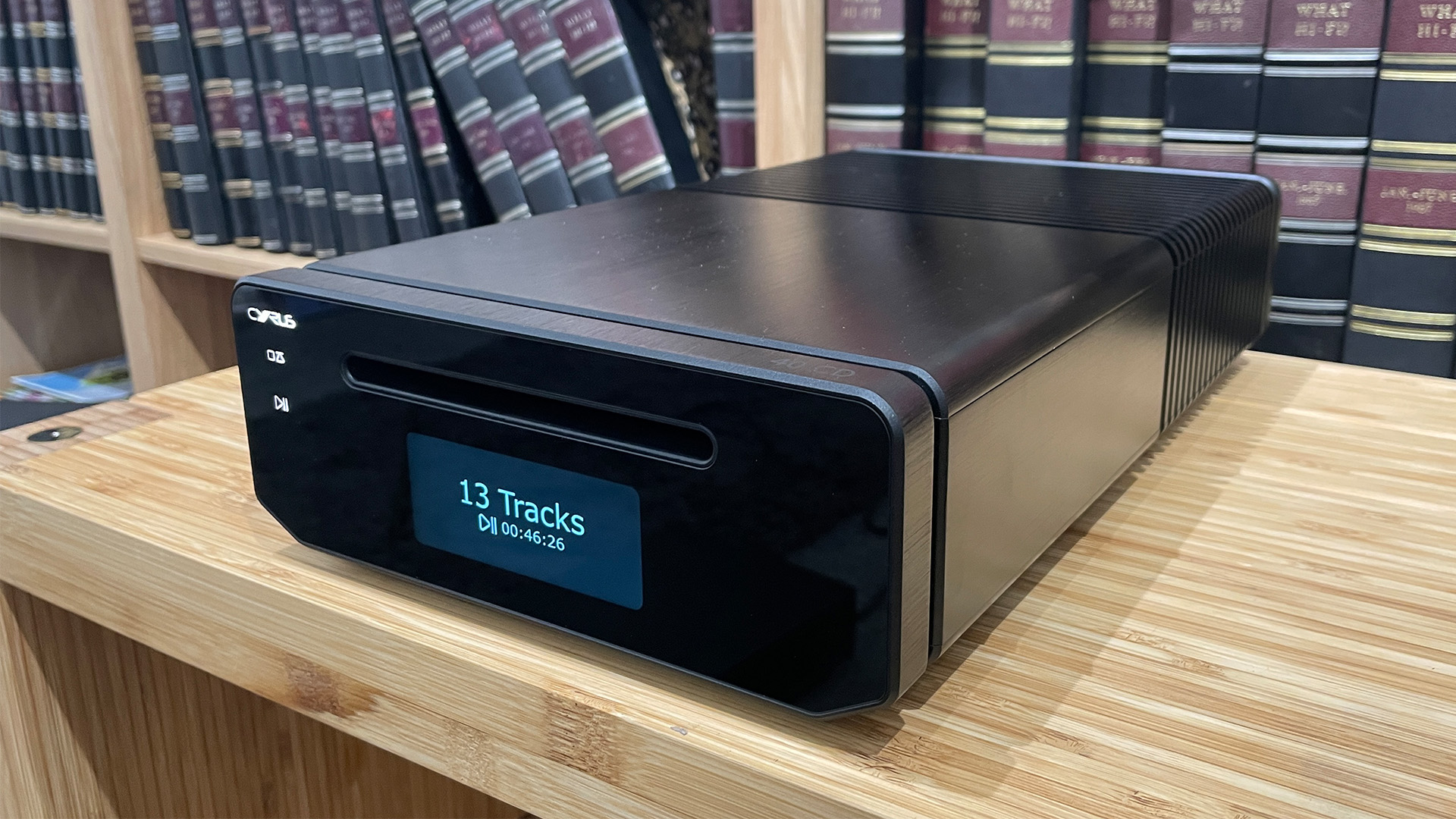 Cyrus 40 CD CD player on wooden hi-fi rack in front of book case, display reads 13 tracks