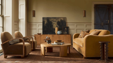 Mustard sofa and two armchairs in neutral livin room with coffee table and sideboard 