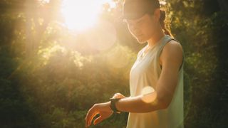 Woman checking fitness tracker, wearing black cap in the sunshine