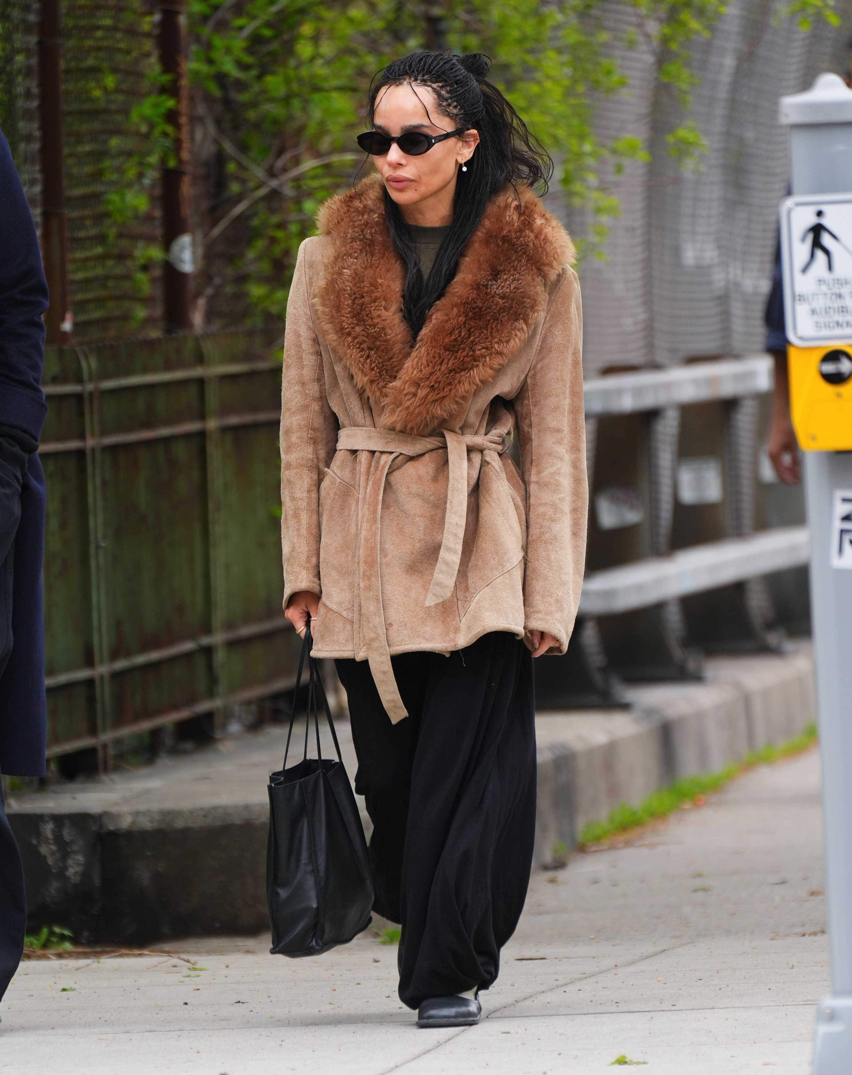 An image of Zoe Kravitz wearing balloon trousers, one of the biggest summer trouser trends of 2026, with a fur-trimmed jacket, loafers and her engagement ring from Harry Styles.