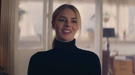 Lisa in black turtleneck sweater smiling sarcastically at Dan in Over Your Dead Body