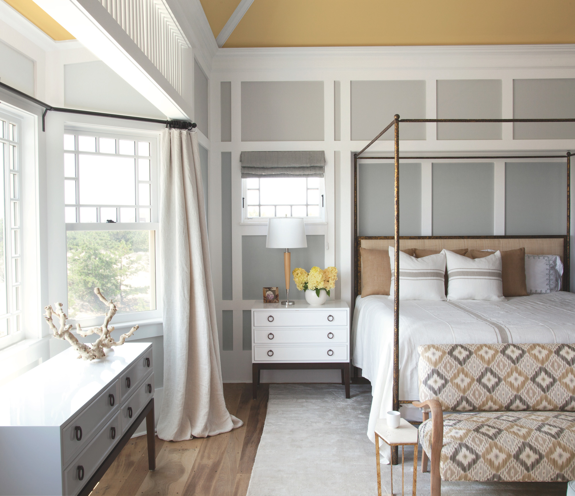 a light grey bedroom with white wall panelling and a yellow ceiling