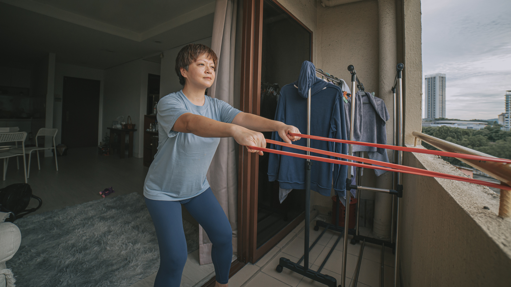 Woman exercises with resistance band on balcony