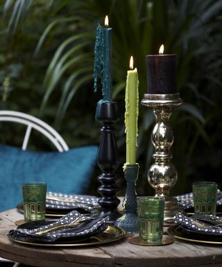 green and blue candles in metallic candle holders on a garden table