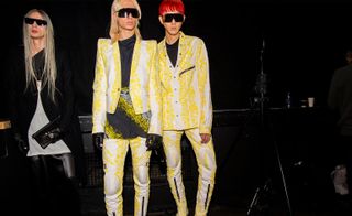 Three male models, two are wearing yellow and white suite like outfits