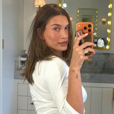 Hailey Bieber taking a mirror selfie with a glowing makeup look
