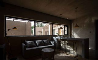 Oversized vitrine windows are oriented to catch the winter sun, the light warming the shaded minimalist interiors lined with concrete walls, deep sofas, and narrow clerestories.