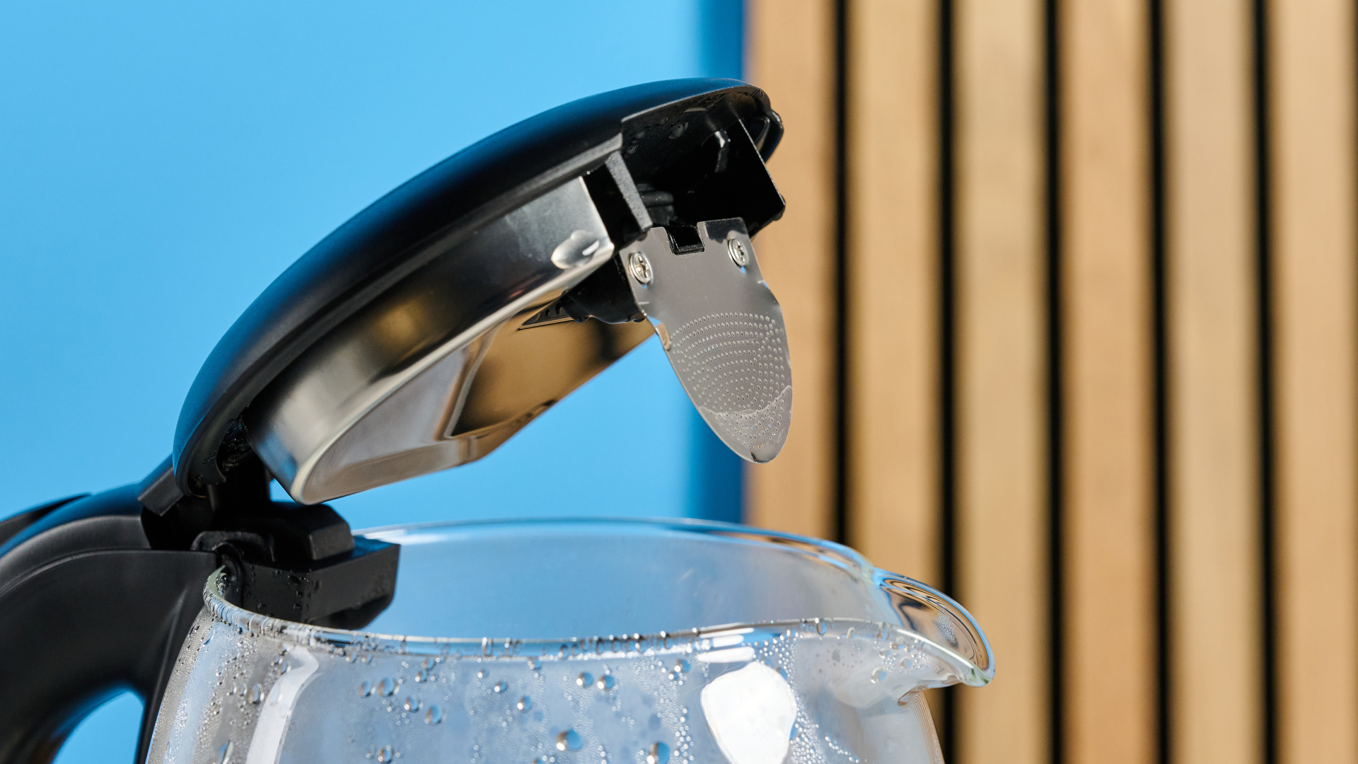 The spout of the Cosori Electric Glass Kettle photographed in front of a blue background.