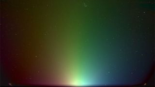 a colorful gradient of light seen against a starry background