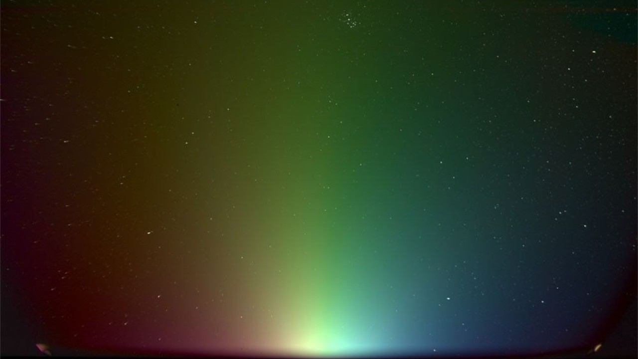 a colorful gradient of light seen against a starry background