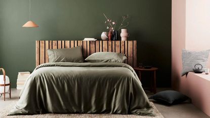 Some of the most popular bedding, Ettitude Signature Sateen Sheets on a wood bed frame against an olive green wall.