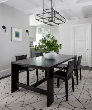 A white dining room with black table and chairs, and a statement lantern-style light fitting